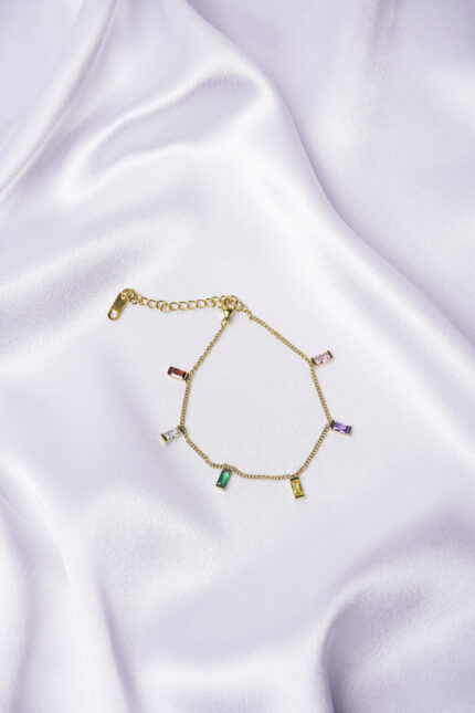 Dainty curb chain bracelet in a gold-tone finish, accented with tiny dangling rectangular gemstones in various colors and a lobster claw clasp