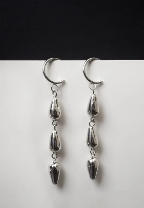 Trendy mini C-hoop earring with a polished silver/golden-tone chain links suspends three polished teadrop charms and a small vintage-inspired coin charm, push-back post