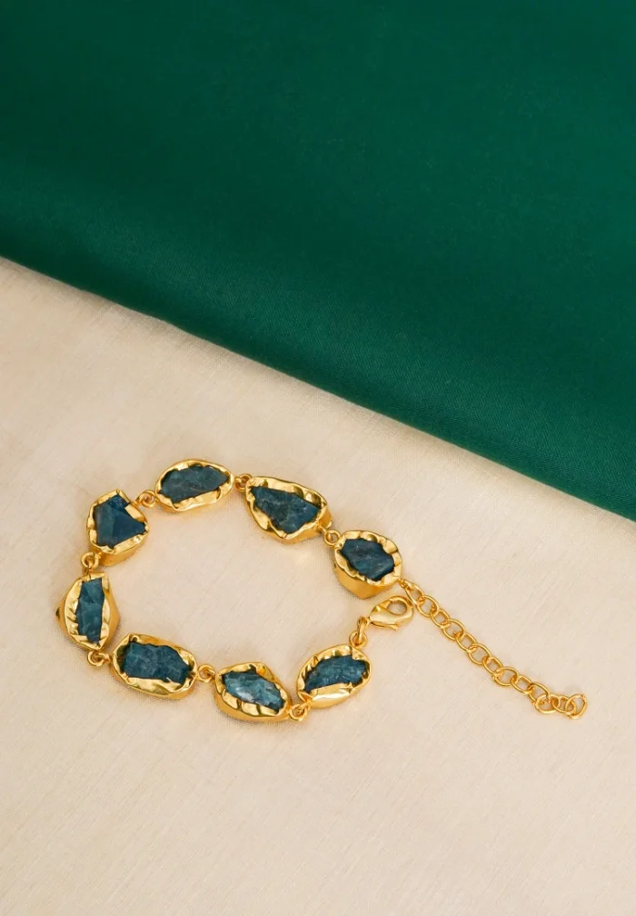 Handcrafted metal bracelet in a polished golden tone with an emerald finish, showcasing irregular purple raw gemstones placed evenly along the design, completed with a lobster claw clasp.