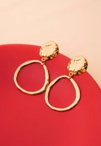 Chic asymmetrical circular earrings with a textured gold-tone disc, an organic finish, and a comfortable push-back fastening.