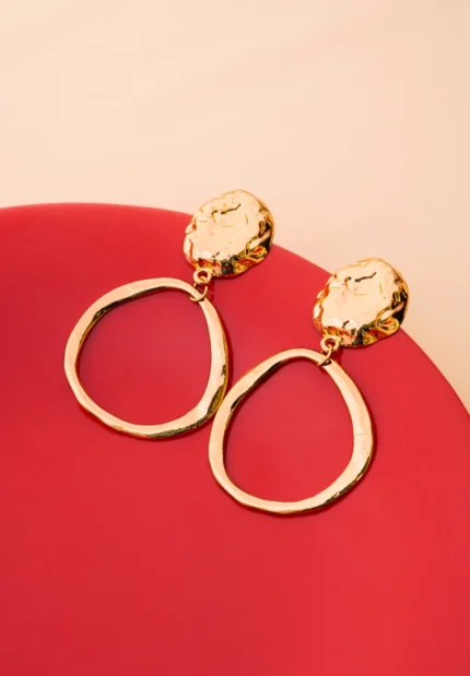 Chic asymmetrical circular earrings with a textured gold-tone disc, an organic finish, and a comfortable push-back fastening.