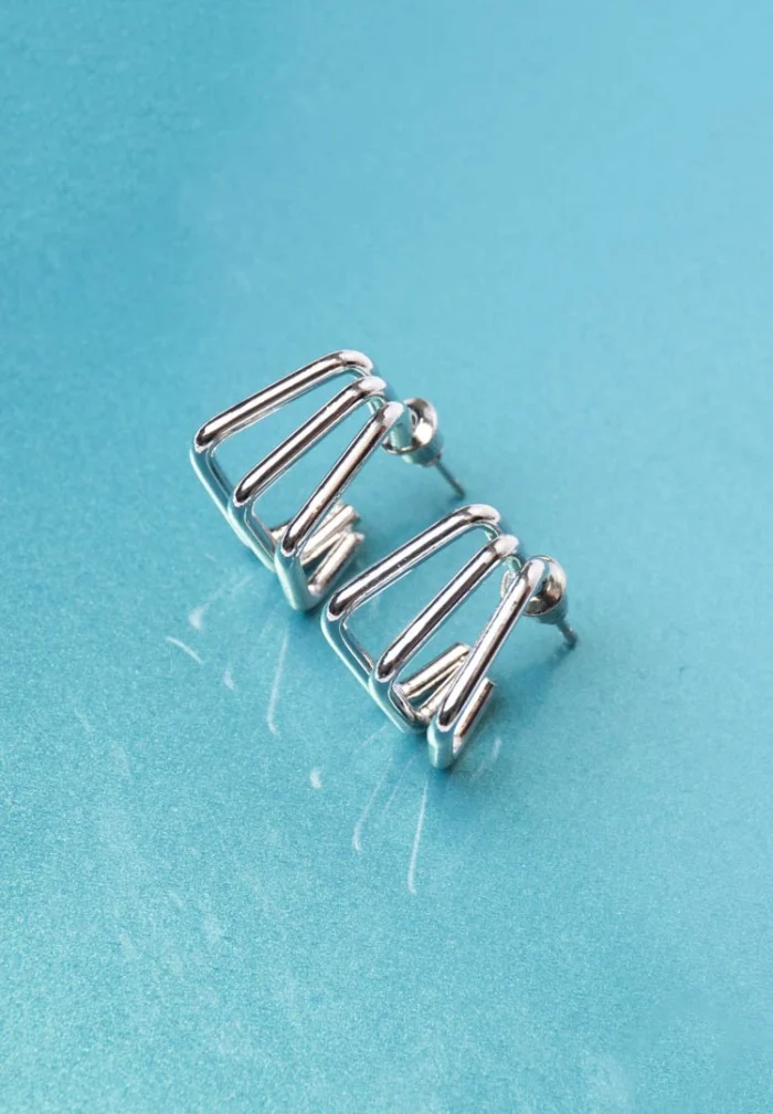 Chic metal hoop earrings featuring a polished silver-tone finish, playful geometric cage, and a push back for easy wear.