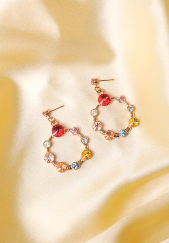 Chic metal hoop earrings featuring a polished golden-tone finish, playful round cage with gemstones, and a push back for easy wear.