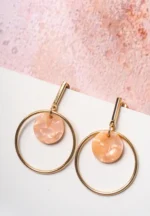 Chic metal hoop earrings featuring a polished golden-tone finish, playful round resin drop, and a push back for easy wear.