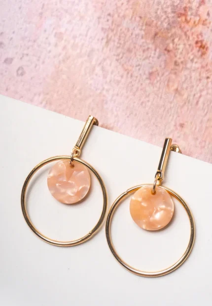 Chic metal hoop earrings featuring a polished golden-tone finish, playful round resin drop, and a push back for easy wear.
