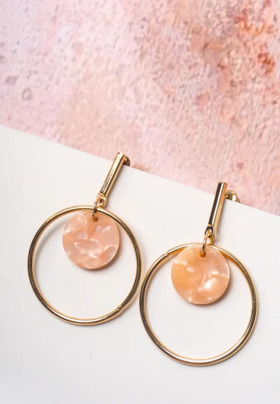 Chic metal hoop earrings featuring a polished golden-tone finish, playful round resin drop, and a push back for easy wear.