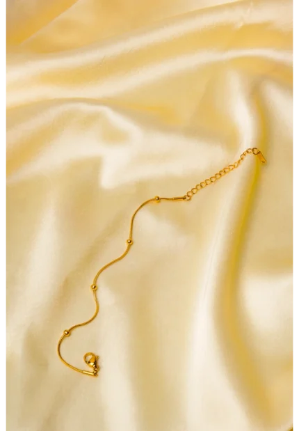Polished gold-tone snake chain bracelet featuring evenly spaced small circular beads and a secure lobster claw clasp