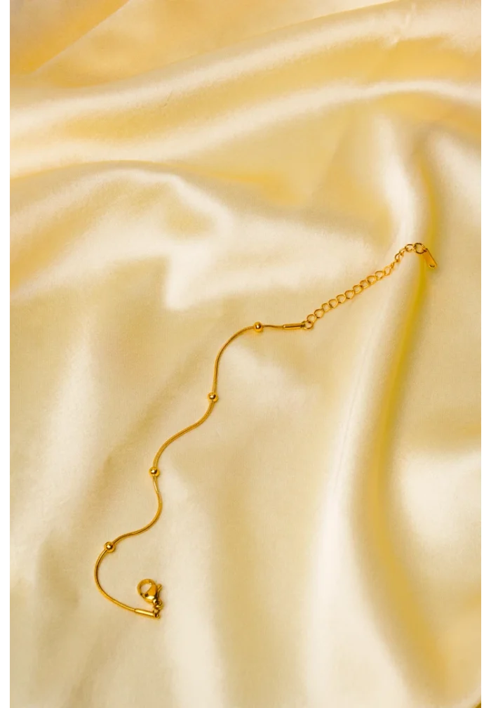 Polished gold-tone snake chain bracelet featuring evenly spaced small circular beads and a secure lobster claw clasp