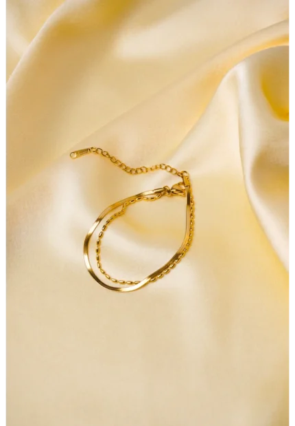 Elegant adjustable curb chain bracelet in a gold-tone finish, featuring a curved metallic wire centerpiece with a dangling spherical charm and a secure spring ring clasp.