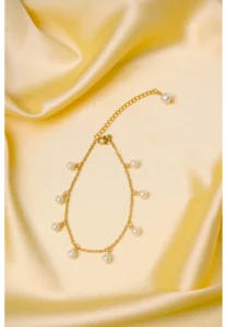 Elegant adjustable curb chain bracelet in a gold-tone finish, featuring a curved metallic wire centerpiece with a dangling spherical charm and a secure spring ring clasp.