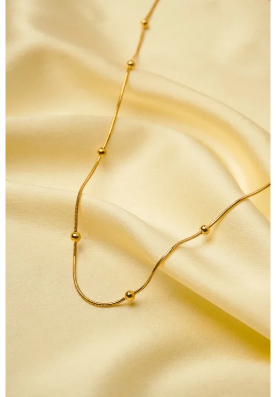 Minimalist gold-tone bracelet with a fine satellite chain, a sleek curved rectangular bar, and a petite orange heart charm, finished with a secure lobster claw clasp.
