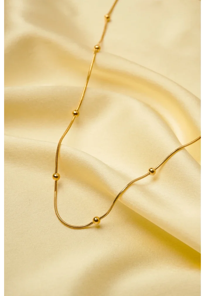 Minimalist gold-tone bracelet with a fine satellite chain, a sleek curved rectangular bar, and a petite orange heart charm, finished with a secure lobster claw clasp.
