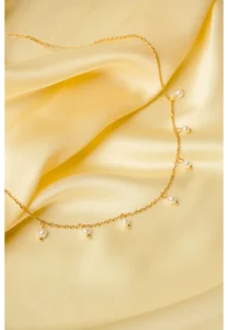 Elegant adjustable curb chain bracelet in a gold-tone finish, featuring a curved metallic wire centerpiece with a dangling spherical charm and a secure spring ring clasp.