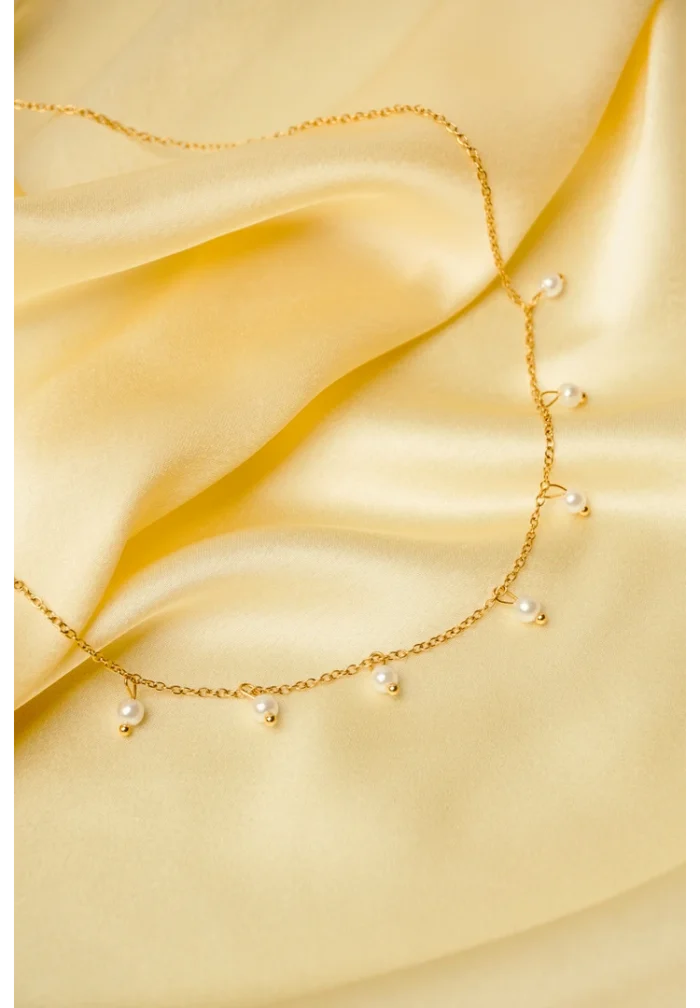 Elegant adjustable curb chain bracelet in a gold-tone finish, featuring a curved metallic wire centerpiece with a dangling spherical charm and a secure spring ring clasp.