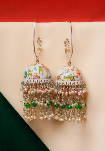 Fusion-style silver-tone jhumka earring featuring intricate floral meenakari artwork,fine chain tassels, and red and green pearl bead embellishments and a curved hook closure
