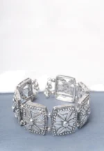 Handcrafted oxidized silver-tone metal cuff bracelet with evenly spaced floral square engravings, circular beadwork, and delicate ghungroo dangles.