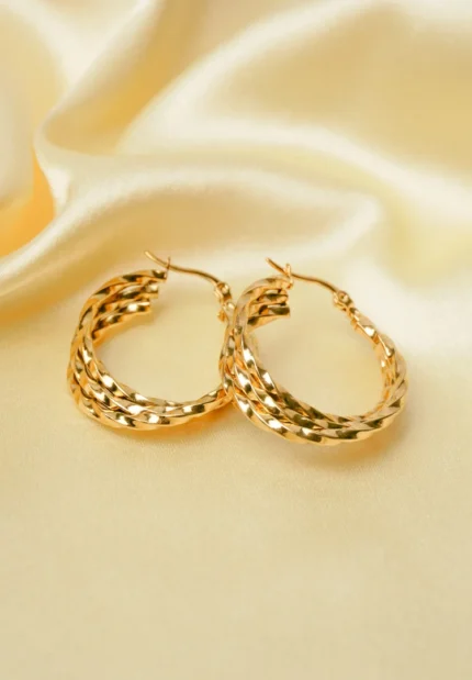 Refined and unique twisted spiral hoop earrings with three interwoven metal strands, a gleaming gold-tone finish, and a hinged back for easy wear.