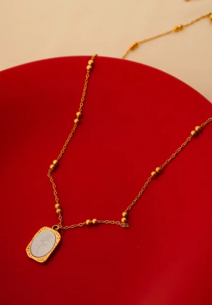 Minimalist gold-tone bracelet with a fine satellite chain, a sleek curved rectangular bar, and a petite orange heart charm, finished with a secure lobster claw clasp.