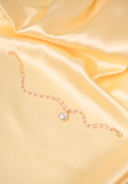 Elegant adjustable curb chain bracelet in a gold-tone finish, featuring a curved metallic wire centerpiece with a dangling spherical charm and a secure spring ring clasp.