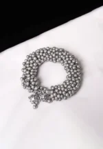 Handcrafted metal bracelet in a polished silver tone designed with ghungroos at the end.