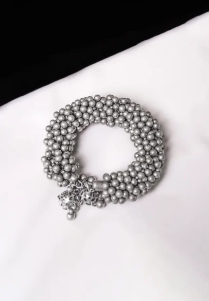 Handcrafted metal bracelet in a polished silver tone designed with ghungroos at the end.