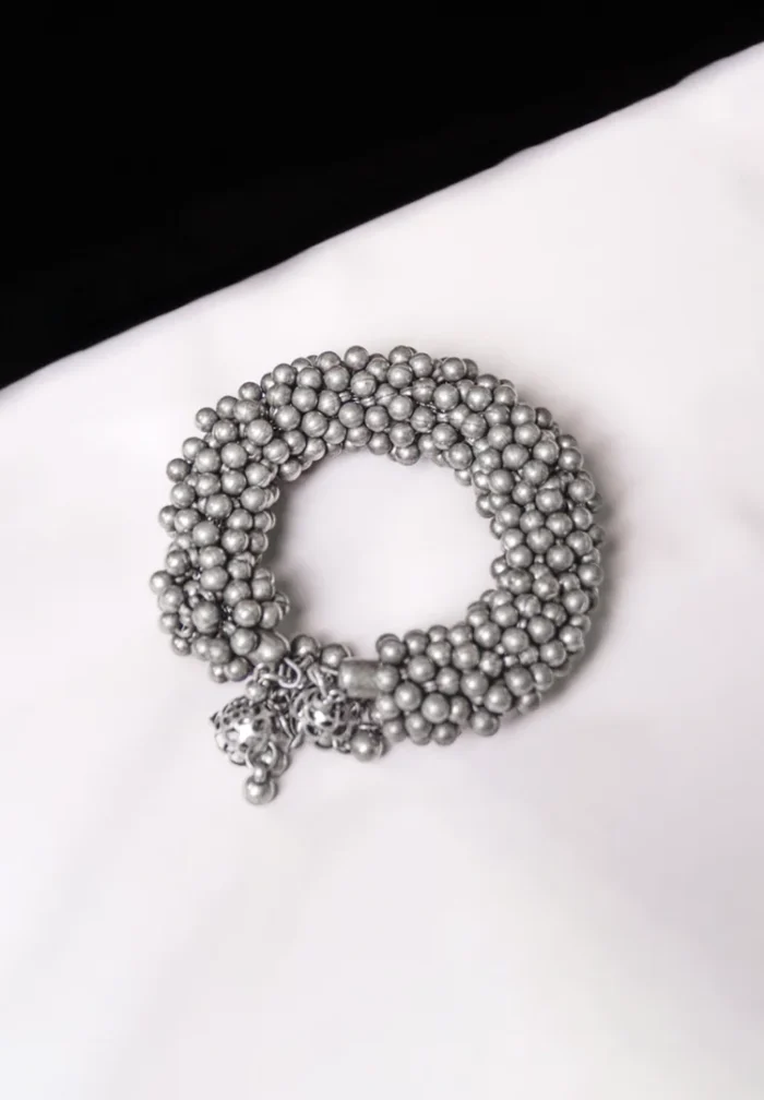Handcrafted metal bracelet in a polished silver tone designed with ghungroos at the end.