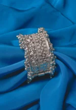 Oxidized silver-tone metal cuff bracelet featuring fine intricate detailing and adorned with ghungroos on both edges.