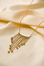 Stylish gold-tone necklace with a filled flat cable chain, an elegant crescent pendant, and fine dangling chains ending in circular golden beads