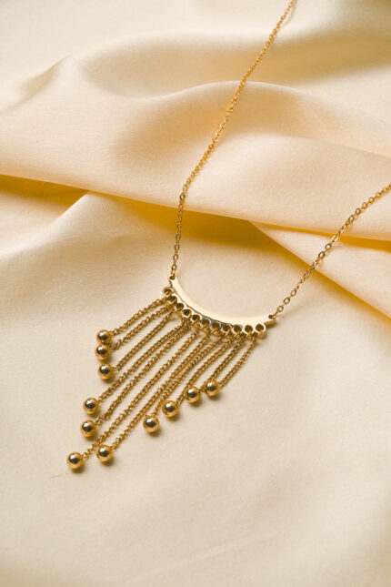 Stylish gold-tone necklace with a filled flat cable chain, an elegant crescent pendant, and fine dangling chains ending in circular golden beads