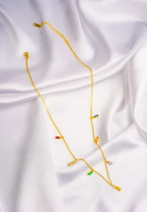 Stylish gold-tone necklace with a filled flat cable chain, an elegant teadrop shaped pendant,with delicate filigree and a green stone in the center and a lobster claw clasp.