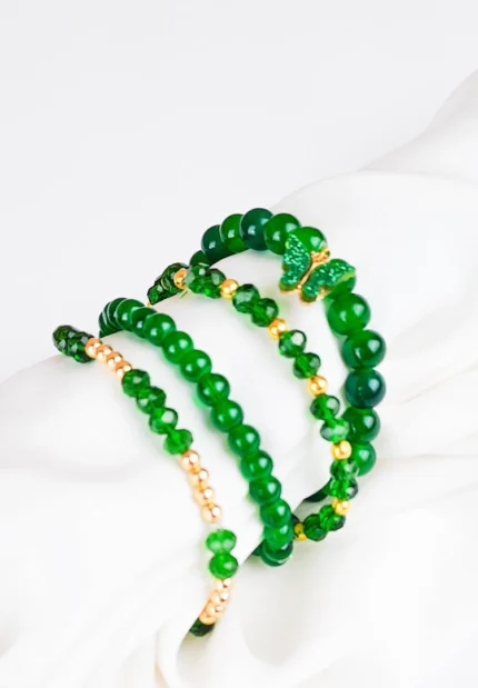 Pack of four green beaded bracelets, two with gold accents, one classic dark green and one with a butterfly charm,