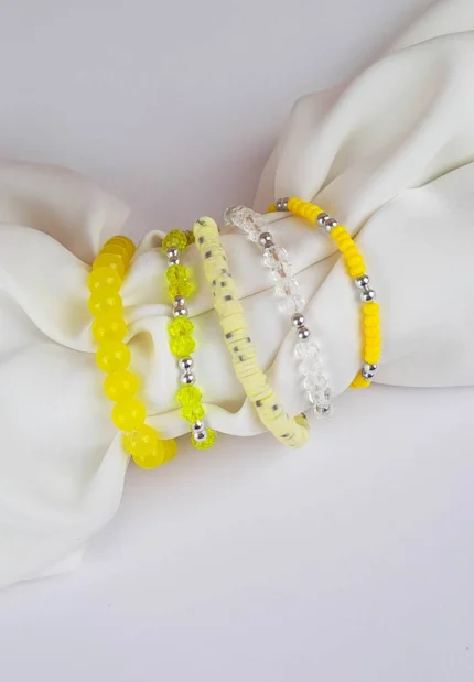 Pack of five yellow, clear, and shell disc beaded stretch bracelets.
