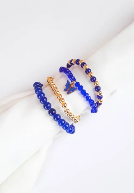 Pack of four royal blue beaded bracelets. One blue, one gold stretch beaded bracelets and two classic beaded bracelets, one with a butterfly charm.