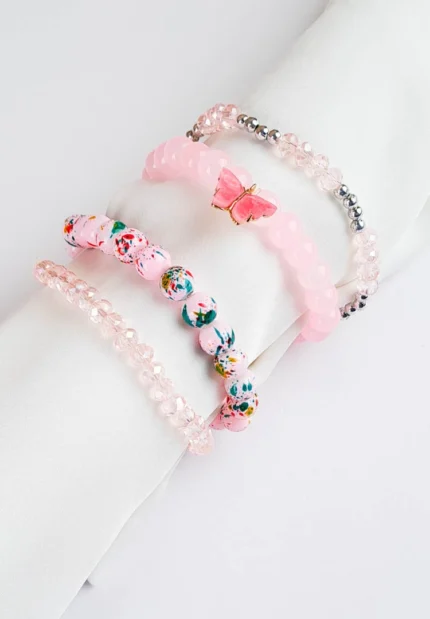 Pack of four pink beaded stretch bracelets, one with speckled beads and one with a butterfly charm