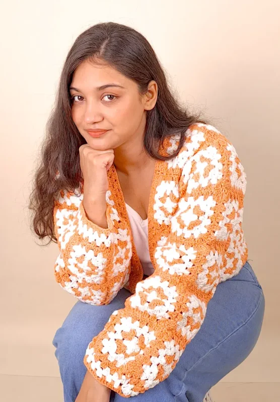 Women’s orange and white crochet cardigan with open-knit detailing.