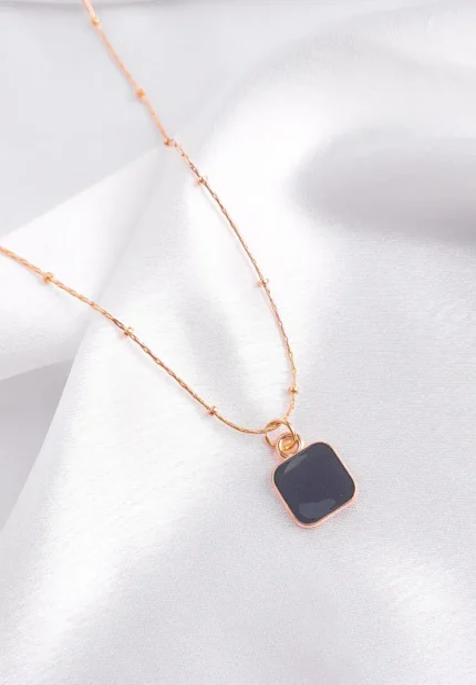  Layered gold-tone necklace with faceted black square pendant and delicate chain details, adjustable clasp.