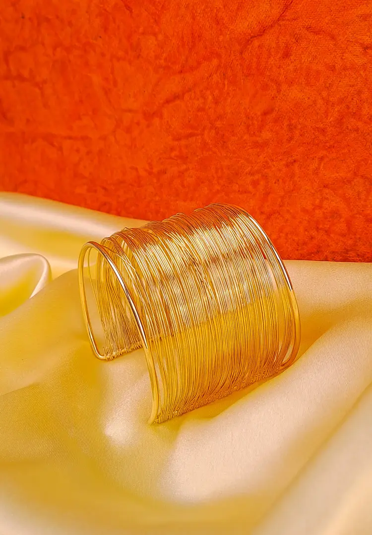 TH (89) Open-ended cuff bracelet made from layered metallic wires with a sculptural polished finish.