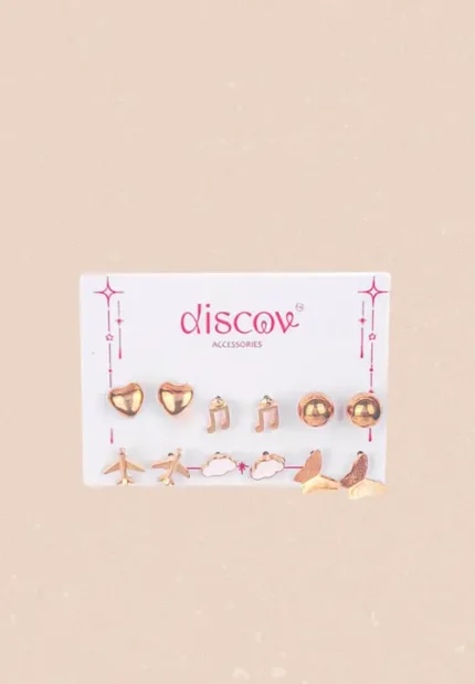 A collection of seven pairs of small, gold-toned stud earrings displayed on a card. The eclectic designs include polished gold spheres, a butterfly, a cloud, musical notes, a heart, and two different styles of airplane studs.