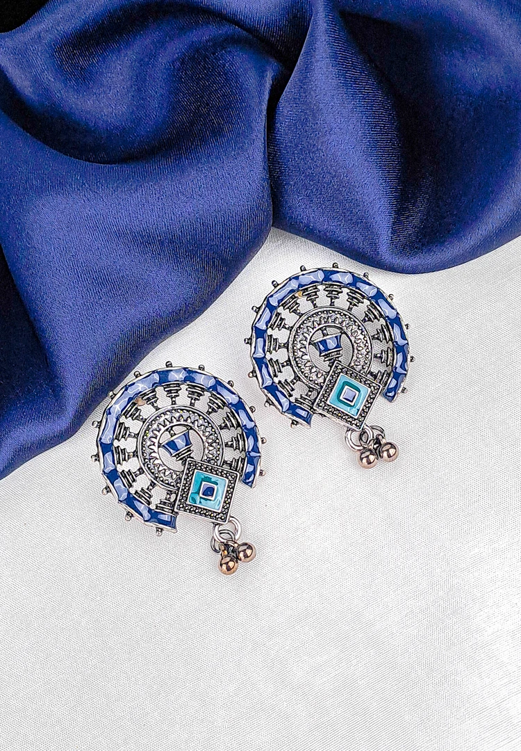 th (15) Oxidized silver half-moon stud earring with blue, brown, and green enamel detailing and a small hanging ghunghroo.