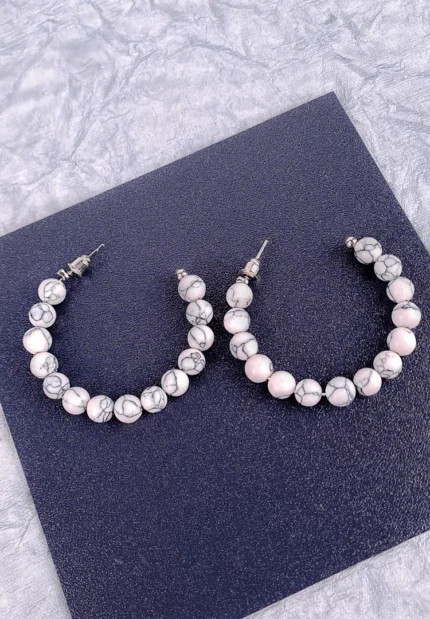 Hoop earrings with white marble beads and gray veining, polished finish, and latch-back closure.