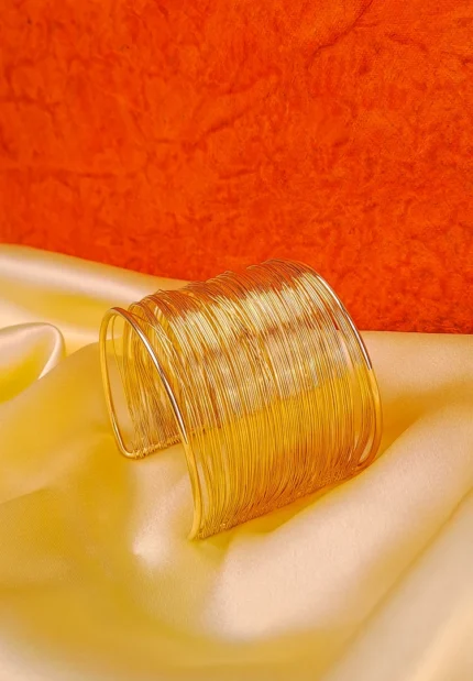 Open-ended cuff bracelet made from layered metallic wires with a sculptural polished finish.