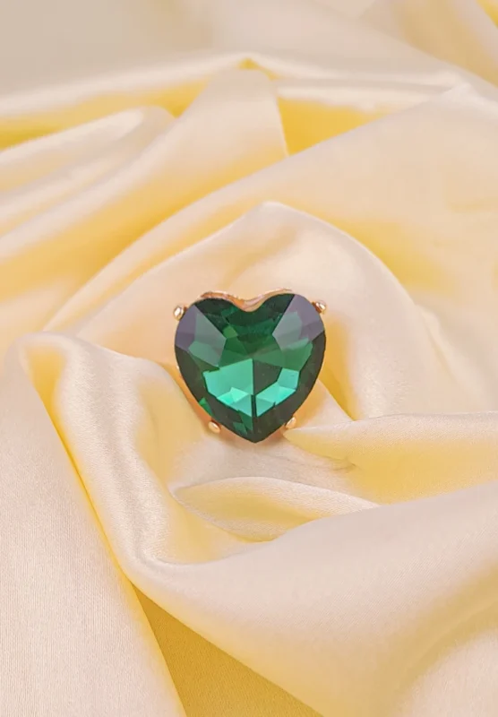 Cocktail ring featuring a faceted heart-shaped green stone in polished prong mount with filigree accents.