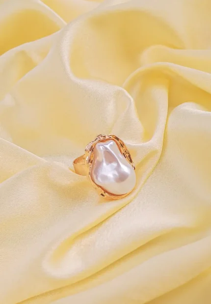 Statement ring with large baroque-style faux pearl and sculpted metallic bezel on an adjustable band.