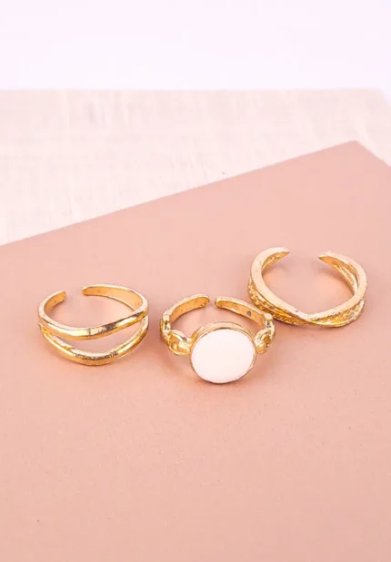 This set of three adjustable, open gold-toned rings is designed for stacking. It includes a minimalist double-band cuff, an Enamel Orbit Ring with a white focal point, and a richly textured wide statement cuff.