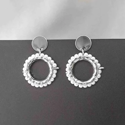 Round silver hoop earrings framed with pearls, featuring reflective studs and push-back closures.