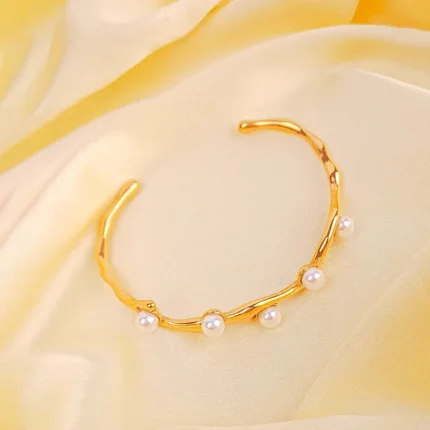 Gold wavy open cuff bracelet with faux pearl accents and glossy finish