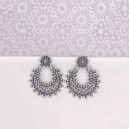 Large, crescent-shaped oxidized silver drop earring, also known as a Chandbali, featuring a highly textured surface of dense, tiny seed bead clusters and a small floral stud at the top.