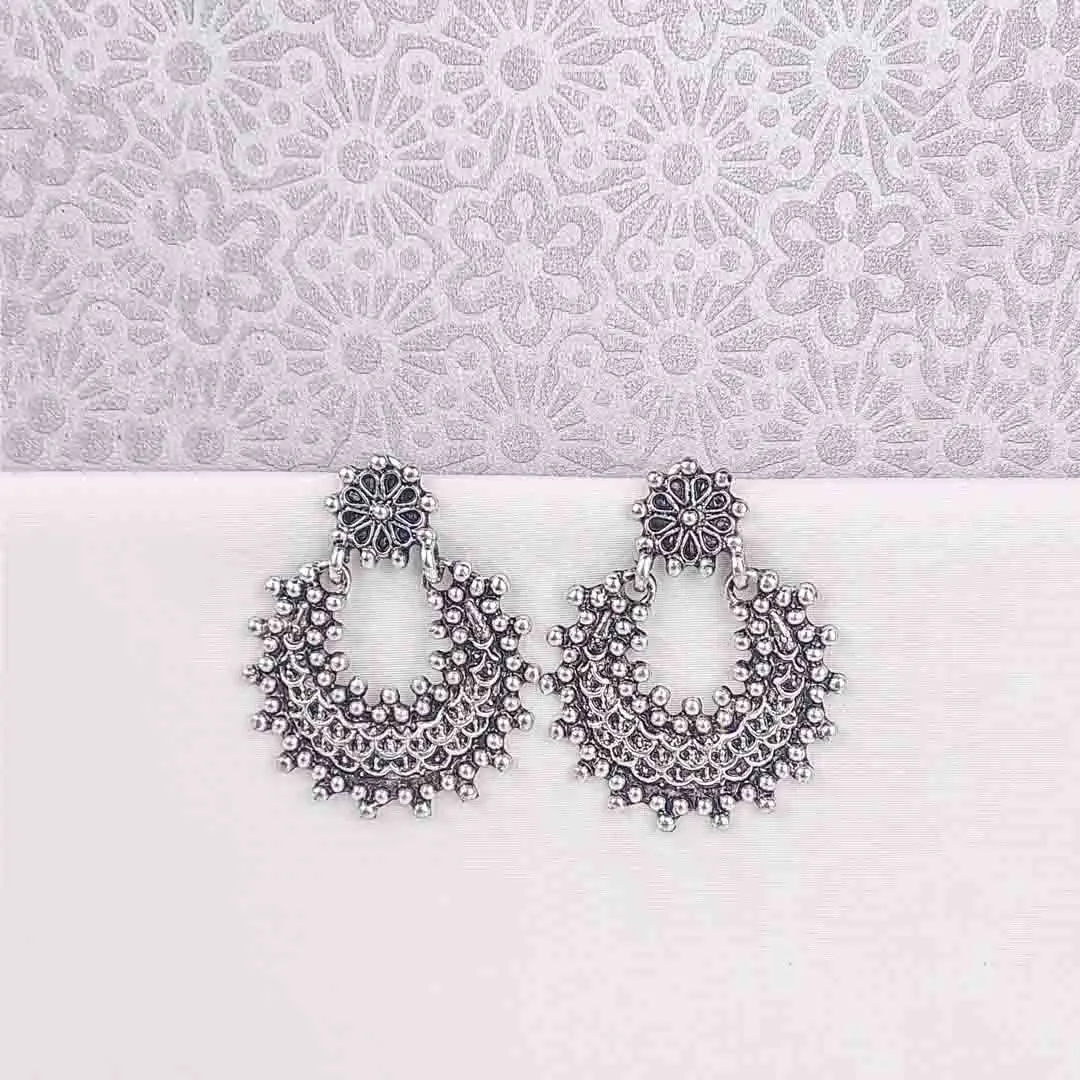 20251105_131119 Large, crescent-shaped oxidized silver drop earring, also known as a Chandbali, featuring a highly textured surface of dense, tiny seed bead clusters and a small floral stud at the top.