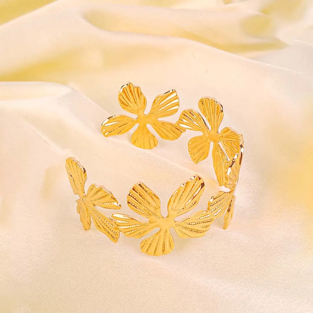 20251120_104706 a wide, gold-colored open-cuff bracelet decorated with an array of individual flower motifs