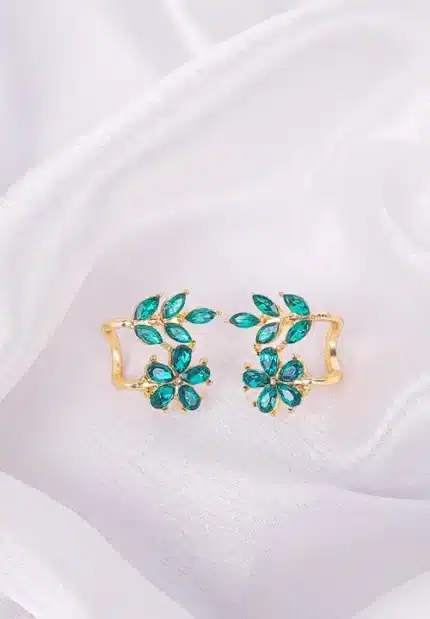 Ear cuffs with floral and leaf motif, emerald-toned crystals, polished metal, and secure push-back closure.